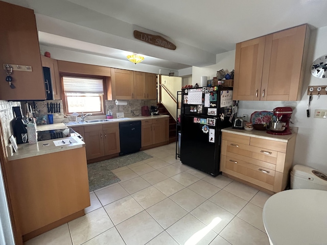 kitchen with light tile patterned floors, tasteful backsplash, light countertops, a sink, and black appliances