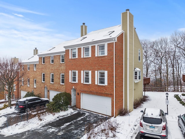 exterior space featuring an attached garage, a chimney, fence, and brick siding