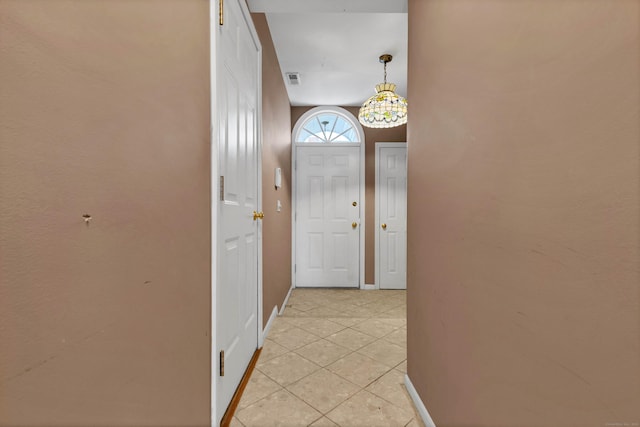 corridor featuring light tile patterned floors, visible vents, and baseboards