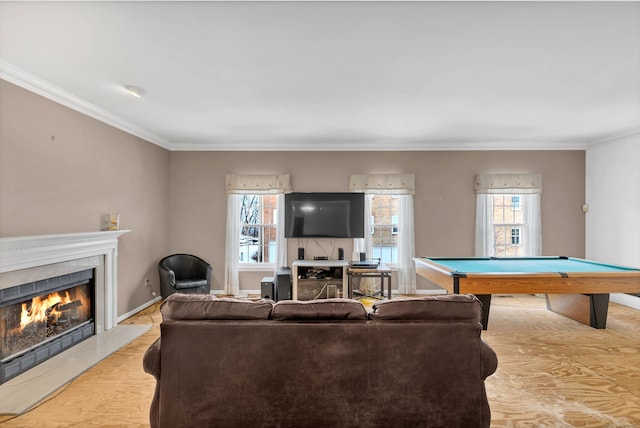 living area with a warm lit fireplace, wood finished floors, billiards, baseboards, and ornamental molding