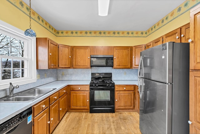 kitchen with black appliances, brown cabinetry, and a sink