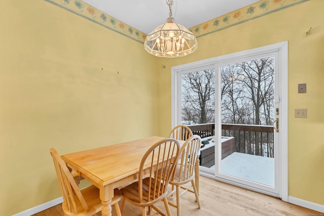 dining room with light wood finished floors, baseboards, and an inviting chandelier