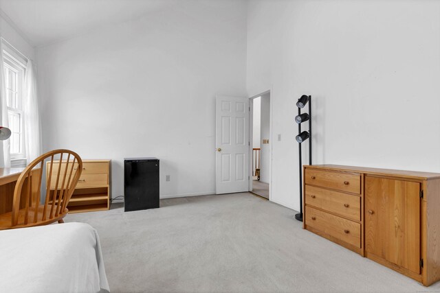 bedroom with a high ceiling and light colored carpet