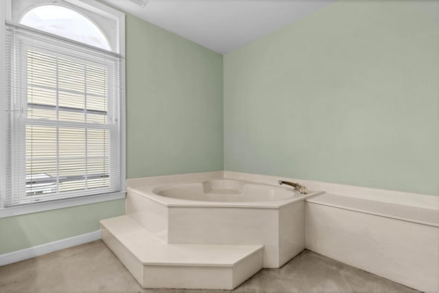 bathroom featuring a garden tub, visible vents, baseboards, and a wealth of natural light