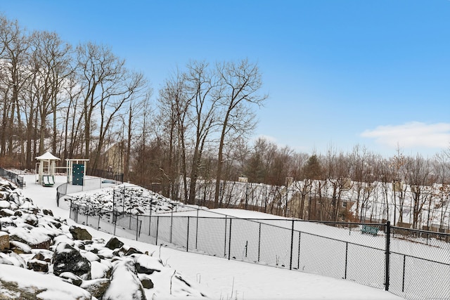 yard layered in snow featuring a playground and fence