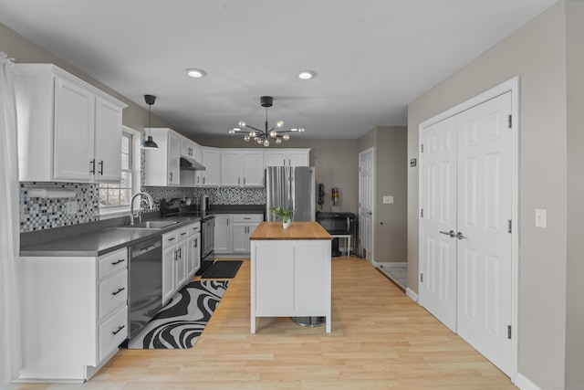 kitchen featuring butcher block counters, a center island, black appliances, white cabinetry, and pendant lighting