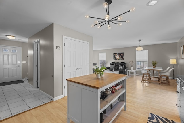 kitchen featuring light wood finished floors, butcher block counters, a kitchen island, open floor plan, and pendant lighting