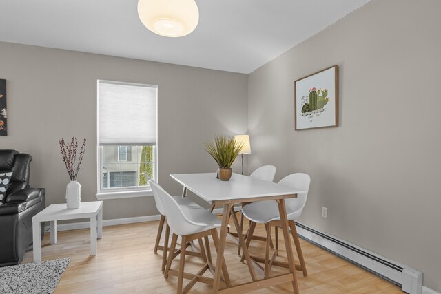 dining space with light wood finished floors, baseboard heating, and baseboards