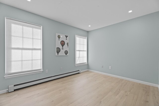 empty room featuring a baseboard radiator, light wood-style flooring, baseboards, and recessed lighting