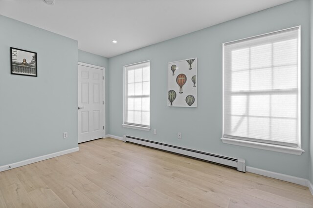 empty room with light wood-type flooring, baseboards, and baseboard heating