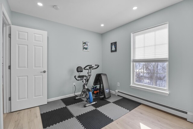 workout area with baseboards, baseboard heating, wood finished floors, and recessed lighting