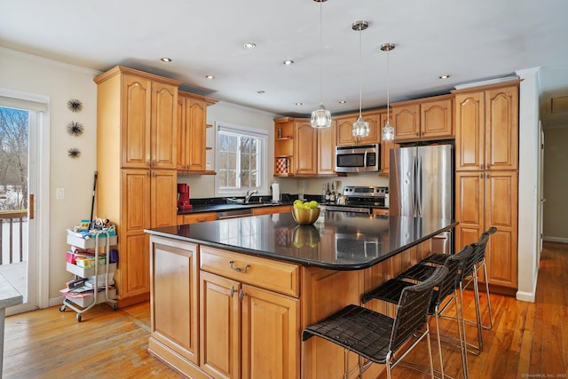 kitchen with hanging light fixtures, dark countertops, a kitchen island, and appliances with stainless steel finishes