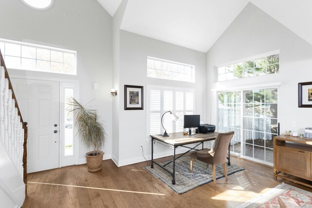 office featuring baseboards, high vaulted ceiling, and wood finished floors