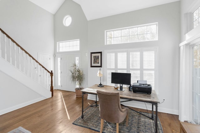 office space with high vaulted ceiling, wood finished floors, and baseboards