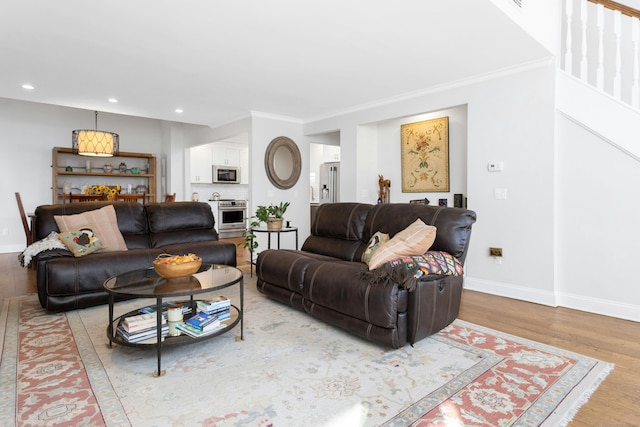 living room with light wood-type flooring, crown molding, baseboards, and recessed lighting