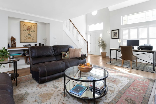 living area with stairs, wood finished floors, and crown molding