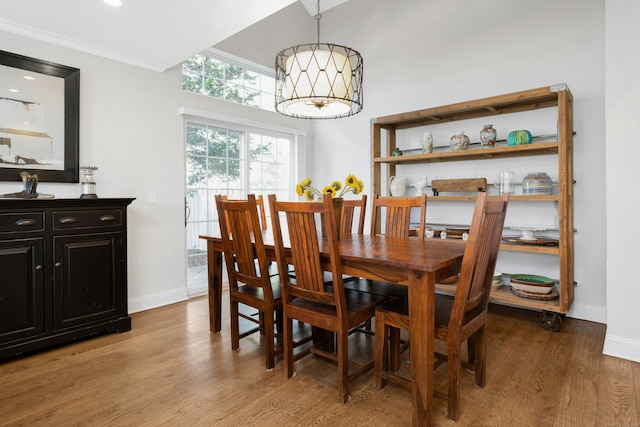 dining room with baseboards, ornamental molding, light wood-type flooring, and a notable chandelier