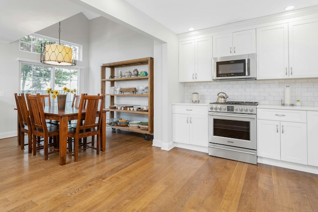 kitchen featuring stainless steel appliances, light countertops, light wood-style flooring, and tasteful backsplash