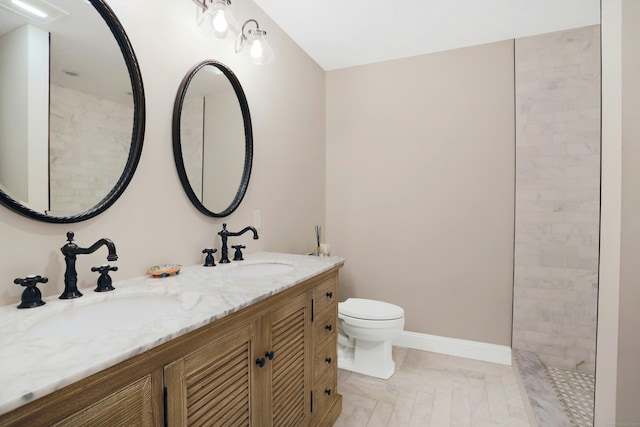 bathroom with baseboards, a sink, toilet, and double vanity