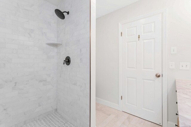 full bath with a tile shower and baseboards