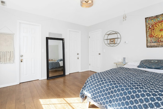 bedroom featuring wood finished floors, visible vents, and baseboards