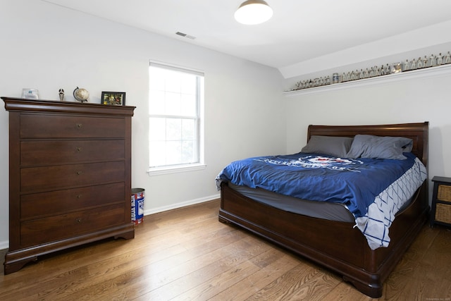 bedroom featuring wood finished floors, visible vents, and baseboards