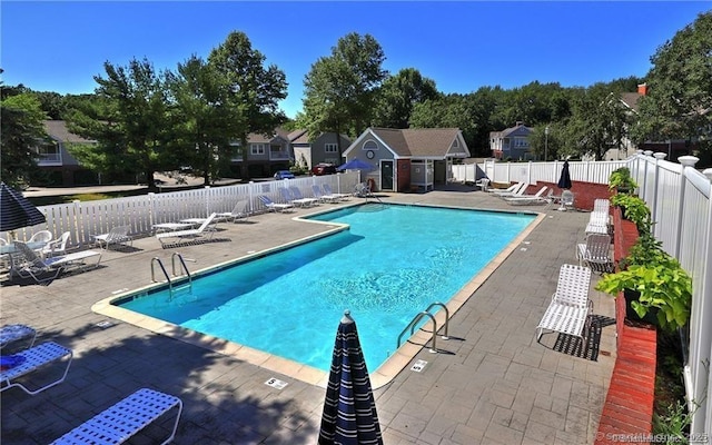 pool featuring a patio area, a fenced backyard, and an outdoor structure