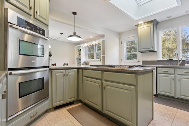 kitchen with light tile patterned floors, stainless steel appliances, a sink, dark countertops, and pendant lighting