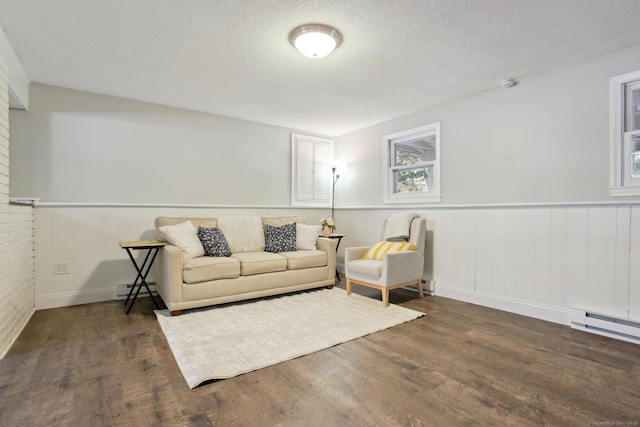 living area featuring dark wood-style floors, a baseboard radiator, wainscoting, and a textured ceiling