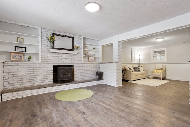 unfurnished living room featuring a textured ceiling, a wainscoted wall, wood finished floors, and built in features