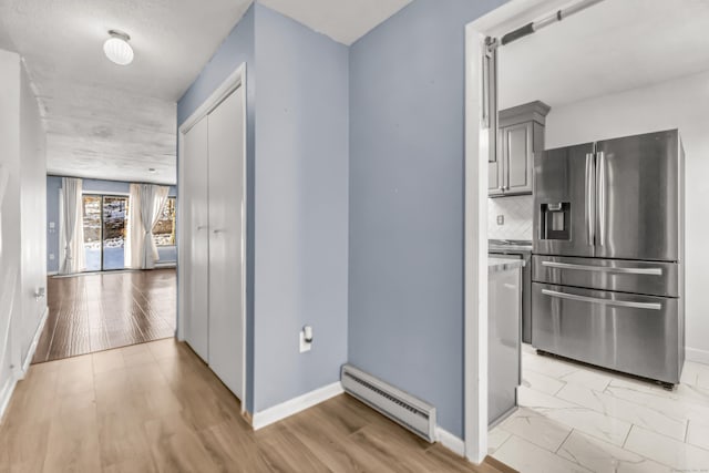 hallway with light wood-style floors, baseboards, and baseboard heating