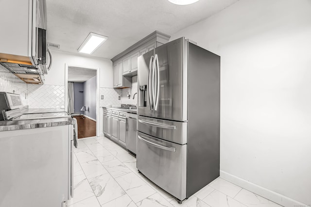 kitchen with marble finish floor, stainless steel appliances, gray cabinets, decorative backsplash, and baseboards