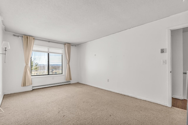 carpeted spare room with a baseboard heating unit, a textured ceiling, and baseboards