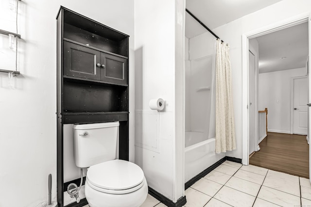 bathroom featuring toilet, shower / tub combo, baseboards, and tile patterned floors