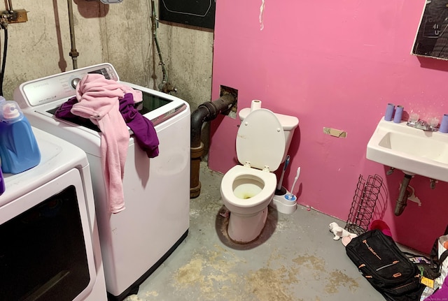 bathroom with toilet, concrete floors, washer and dryer, and a sink