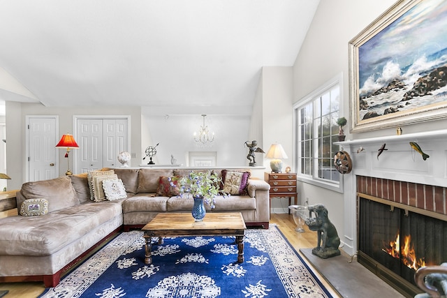 living room featuring lofted ceiling, a fireplace, a chandelier, and wood finished floors