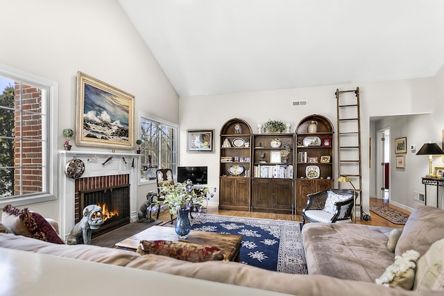 living room featuring high vaulted ceiling, a fireplace, visible vents, and baseboards