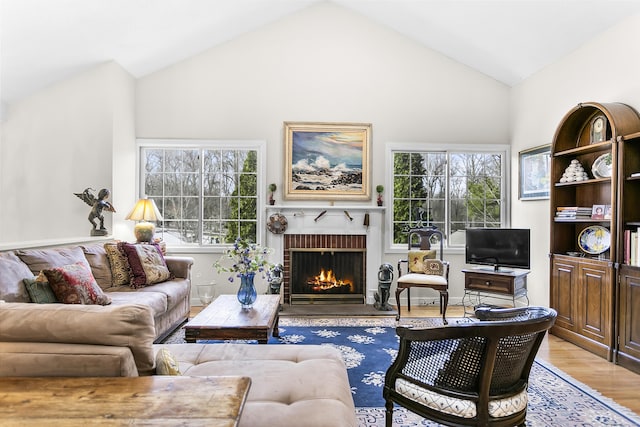 living room featuring lofted ceiling, a brick fireplace, a wealth of natural light, and light wood-style floors