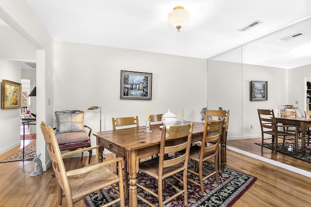 dining room with baseboards, visible vents, and wood finished floors