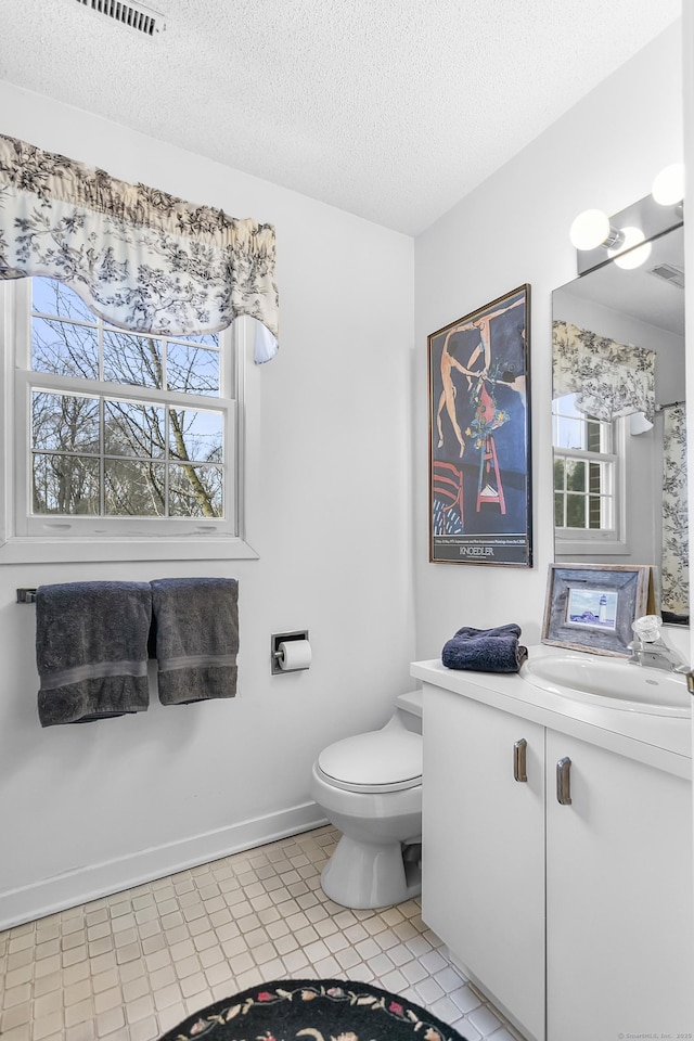 bathroom featuring toilet, baseboards, a textured ceiling, and vanity