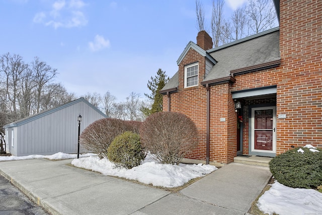 exterior space featuring a shingled roof, a chimney, and brick siding