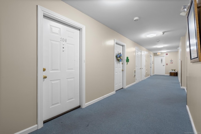 hallway with dark carpet and baseboards