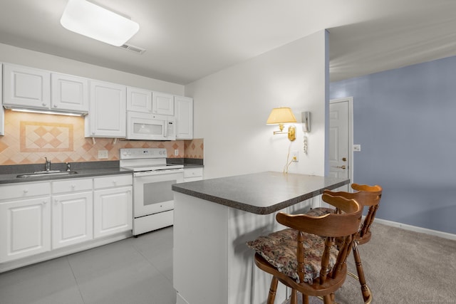 kitchen featuring dark countertops, white appliances, white cabinets, and a kitchen breakfast bar