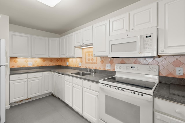 kitchen featuring dark countertops, white appliances, white cabinets, and a sink