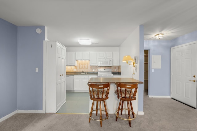 kitchen featuring a breakfast bar, white appliances, white cabinets, and light colored carpet