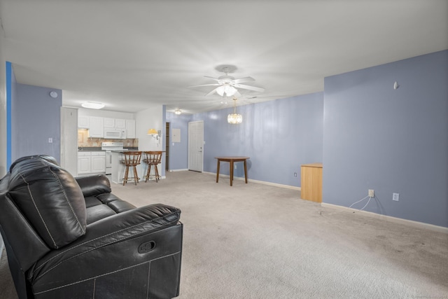 living area with light carpet, ceiling fan, and baseboards