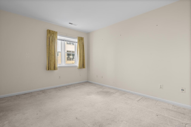 empty room featuring light colored carpet, visible vents, and baseboards