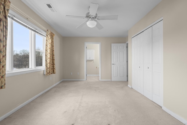 unfurnished bedroom featuring a closet, light colored carpet, visible vents, ceiling fan, and baseboards