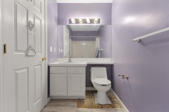 bathroom featuring toilet, a shower with shower curtain, vanity, wood finished floors, and baseboards