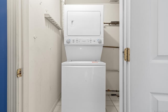 laundry area featuring light tile patterned floors, stacked washer and dryer, and laundry area